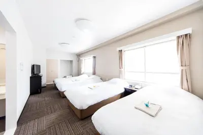 a hotel room with three beds and a window at Best Hotel in Tokyo