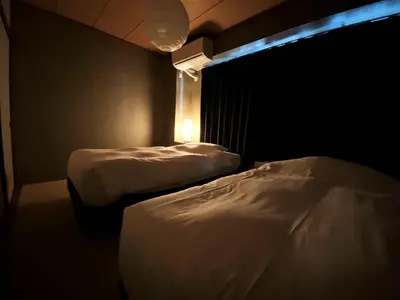 two beds in a room with a light on the wall at Randor Residence Tokyo Classic in Tokyo