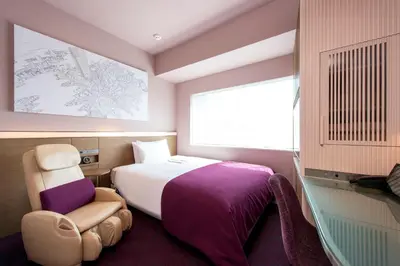a bedroom with a bed and a chair and a window at remm Roppongi in Tokyo