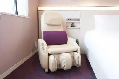 a white chair in a room next to a bed at remm Roppongi in Tokyo