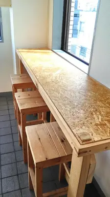 a wooden table and bench with a counter top at Base Inn Komagome Tokyo in Tokyo