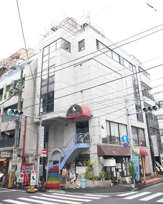 a tall white building with a spiral staircase in front at Base Inn Komagome Tokyo in Tokyo