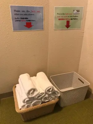 a basket of towels in a bathroom with two signs at Tokyo Guest House Itabashi-juku in Tokyo