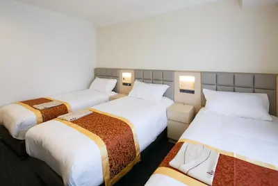 a hotel room with three beds with white sheets at Day Nice Hotel Tokyo in Tokyo