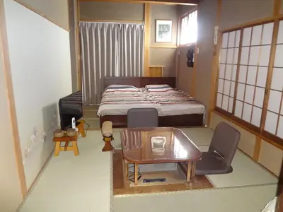 a small room with a bed and a table and chairs at Mokkoan in Tokyo
