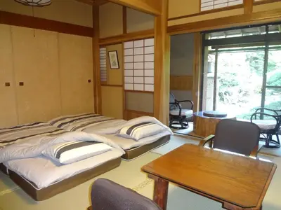 a room with four beds and a table and chairs at Mokkoan in Tokyo