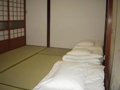 a room with a row of white beds in it at Keys House in Tokyo