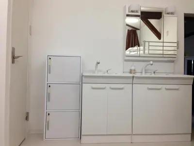 a kitchen with white cabinets and a sink and a mirror at Keys House in Tokyo
