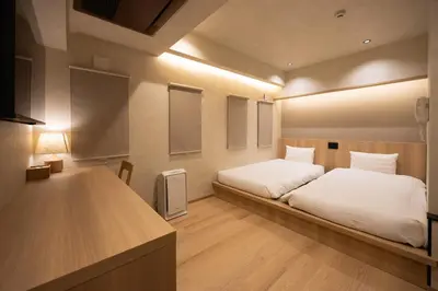 a bedroom with a bed with white sheets and lights at Hotel Paul House in Tokyo