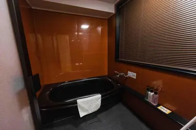 a bathroom with a bath tub and a window at Hotel Paul House in Tokyo