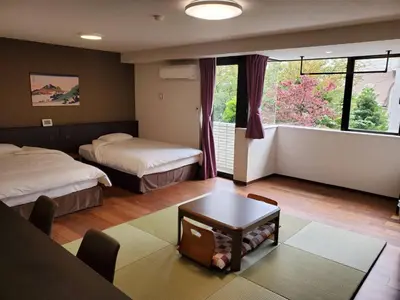 a bedroom with two beds and a table and a window at City Pension Zem in Tokyo