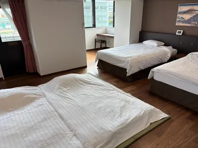 two beds in a hotel room with white sheets at City Pension Zem in Tokyo