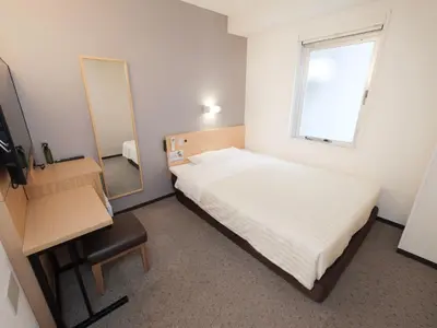 a small bedroom with a bed and a mirror at Super Hotel Ueno-Okachimachi in Tokyo