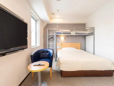 a bedroom with a bed and a tv and a chair at Super Hotel Ueno-Okachimachi in Tokyo
