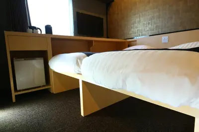a bedroom with a bed with white sheets and a tv at KOKO HOTEL Asakusa Komagata - formerly Hotel Wing International Select Asakusa Komagata in Tokyo
