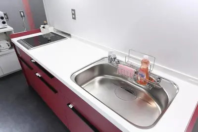 a kitchen with a stainless steel sink and red cabinets at Oak Hotel Edo in Tokyo