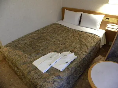 a hotel room with a bed with two towels on it at Hotel New Green Okachimachi in Tokyo