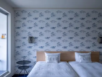 a bedroom with a bed and a blue wall at LYURO Tokyo Kiyosumi by THE SHARE HOTELS in Tokyo