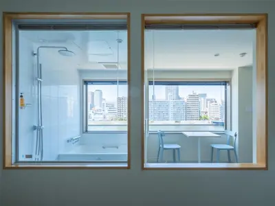 a bathroom with a shower and a table with chairs at LYURO Tokyo Kiyosumi by THE SHARE HOTELS in Tokyo