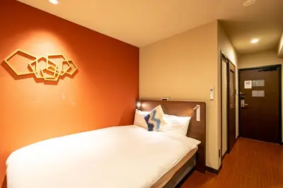a bedroom with a white bed with an orange wall at Red Roof Inn Kamata / Haneda Tokyo in Tokyo