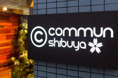 a sign on a building with a comium shuquivula at commun SHIBUYA (Male Only) in Tokyo