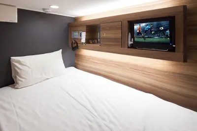 a bedroom with a bed with a flat screen tv at commun SHIBUYA (Male Only) in Tokyo
