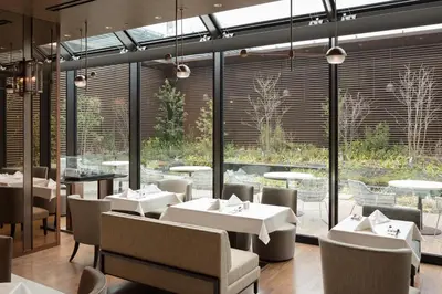 a restaurant with white tables and chairs and large windows at Ascott Marunouchi Tokyo in Tokyo