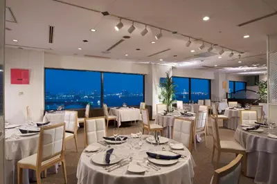 a restaurant with white tables and chairs and large windows at Bayside Hotel Azur Takeshiba in Tokyo