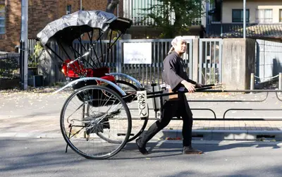 a man walking past a bike on a bench at Yanaka Kotobuki Sou in Tokyo