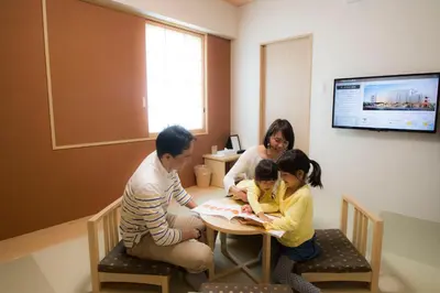 a family sitting at a table reading a book at Hiyori Hotel Maihama in Urayasu