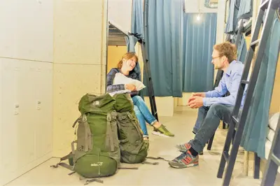 a man and a woman sitting in a room with a backpack at obi Hostel in Tokyo