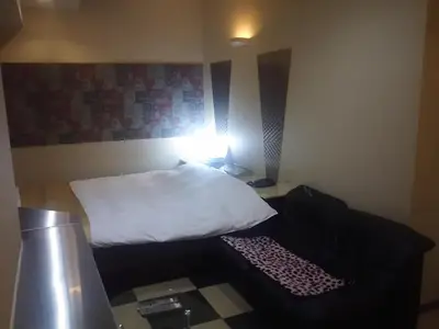a small room with a bed with a white pillow at Hotel Sting in Tokyo
