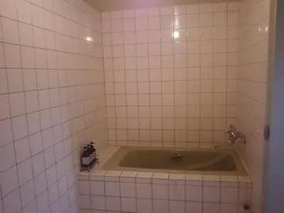 a bath tub in a bathroom with white tiles at Hotel Sting in Tokyo