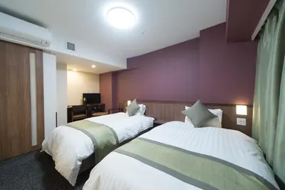 a hotel room with two beds and a purple wall at Dormy Inn Premium Kanda in Tokyo