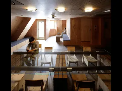 a man sitting at a table in a room with chairs at Do-C Gotanda in Tokyo