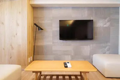 a living room with a table and a tv on a wall at PREMIER suite Shinjuku West 3F 4F in Tokyo