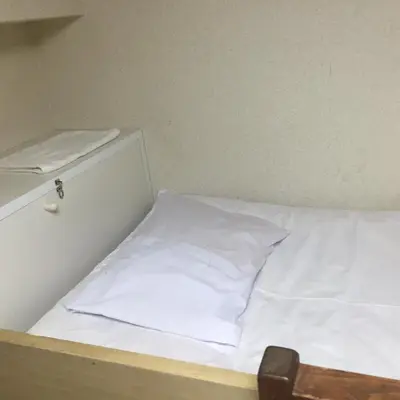 a bed with white sheets and a pillow on it at Yamate Rest House (Male Only) in Tokyo