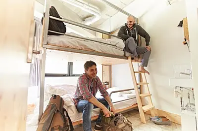 two men sitting in a dorm room with bunk beds at Wise Owl Hostels Shibuya in Tokyo
