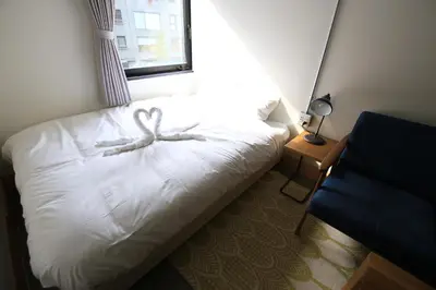 a bedroom with a white bed with a bow on it at Wise Owl Hostels Shibuya in Tokyo