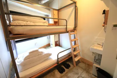 a bunk bed in a room with a ladder and towels at Wise Owl Hostels Shibuya in Tokyo