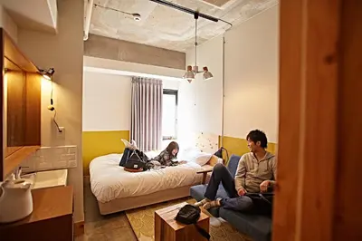 two people sitting on a couch in a living room at Wise Owl Hostels Shibuya in Tokyo