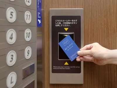 a person holding a credit card in front of an elevator at Keio Presso Inn Tokyo Station Yaesu in Tokyo