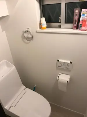a white bathroom with a toilet and a window at Tokyo Ikebukuro Takahashi Minsyuku in Tokyo