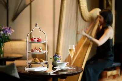a woman is walking by a table with a drink at The Ritz-Carlton, Tokyo in Tokyo