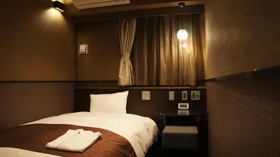 a bedroom with a bed and a table and a window at Hotel SUI Ginza Kyobashi by ABEST in Tokyo