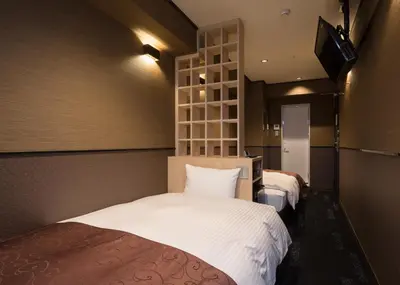 a bedroom with two beds and a tv on the wall at Hotel SUI Ginza Kyobashi by ABEST in Tokyo