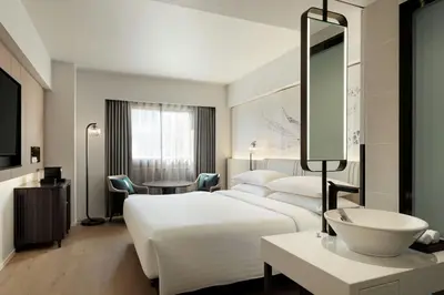 a hotel room with a large white bed and a sink at Courtyard by Marriott Tokyo Ginza Hotel in Tokyo