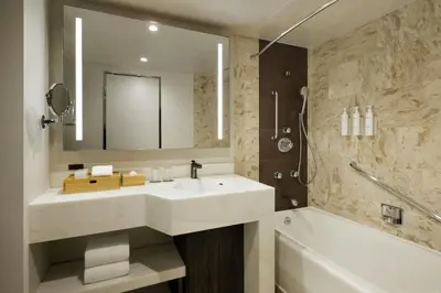 a bathroom with a sink and a tub and a mirror at Courtyard by Marriott Tokyo Ginza Hotel in Tokyo