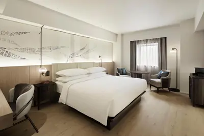 a hotel room with a large white bed and chairs at Courtyard by Marriott Tokyo Ginza Hotel in Tokyo
