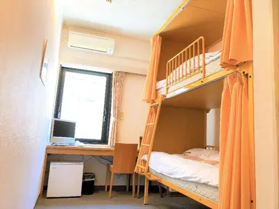 a bedroom with bunk beds with a desk and a computer at Sakura Hotel Ikebukuro in Tokyo